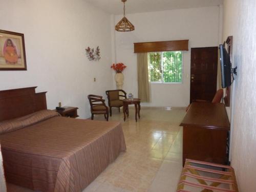 a bedroom with a bed and a table and chairs at Hotel Bajo el Volcan in Cuernavaca