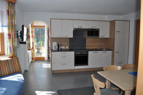 a kitchen with white cabinets and a table and a dining room at Apart Stella Bianca in Kappl
