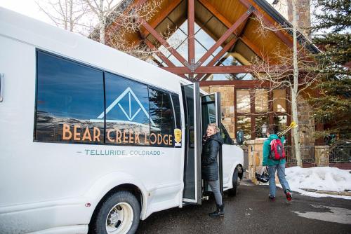 two people are standing outside of a white bus at Bear Creek Lodge in Telluride