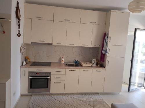 a white kitchen with white cabinets and a sink at Diar Apartment in Durrës