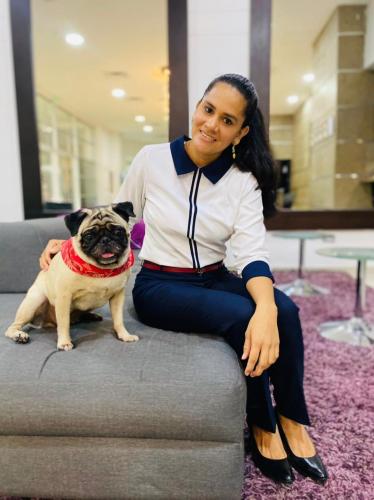 a woman sitting on a couch with a pug dog at Hotel San Silvestre in Barrancabermeja