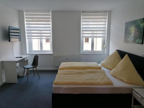a bedroom with a bed and a desk and two windows at Apartment Bona Loca in Aschersleben