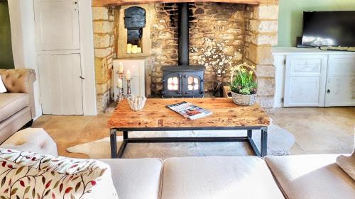 a living room with a wooden table and a fireplace at Magnolia Cottage in Moreton in Marsh