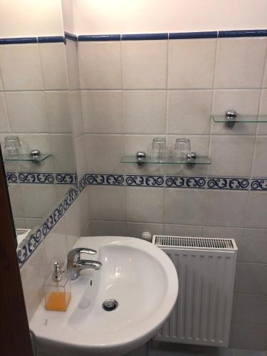 a white bathroom with a sink and a radiator at KARÁM Vendégház és Lakásétterem in Nagybajcs