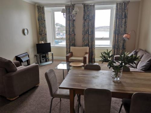 sala de estar con mesa, sillas y TV en Kings Arms Holiday Apartments, en Oban