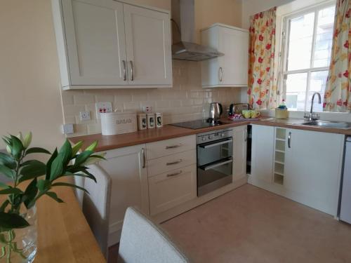a kitchen with white cabinets and a stove top oven at Kings Arms Holiday Apartments in Oban