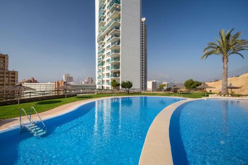 a large blue swimming pool with a tall building at Skyline 20 Apartamento de Lujo con terraza privada y vistas al mar in Benidorm