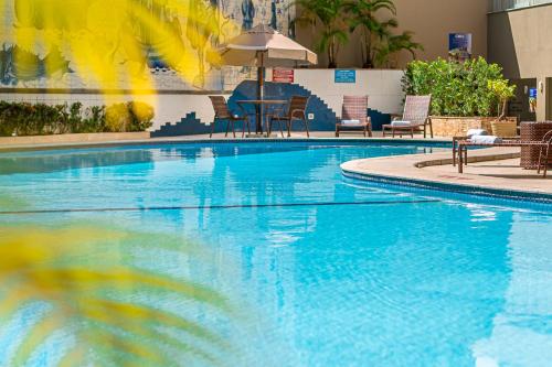 a large blue swimming pool with chairs and an umbrella at Grande Hotel da Barra in Salvador