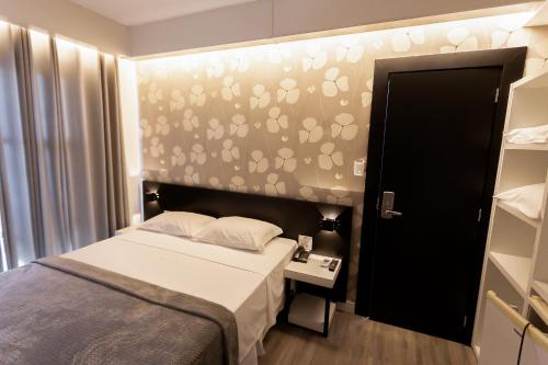 a small bedroom with a bed and a wall with footprints at Hotel Cidade Araxá in Araxá