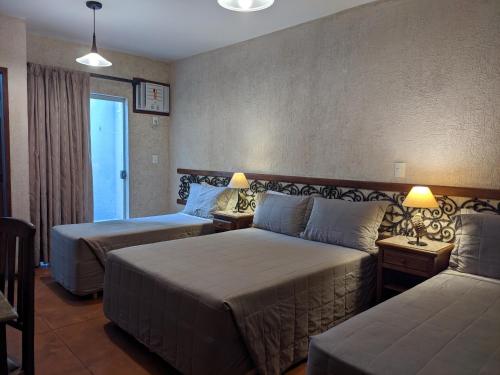 a hotel room with two beds and a couch at Pousada Brasil Nativo in Cabo Frio