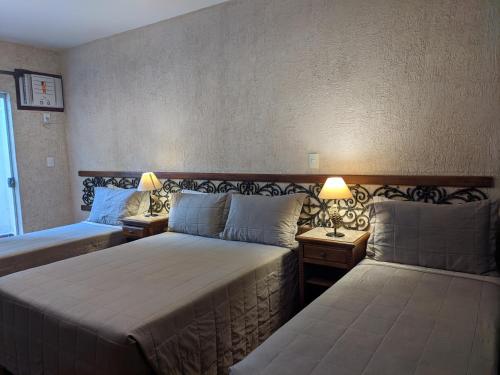 a hotel room with two beds and two lamps at Pousada Brasil Nativo in Cabo Frio