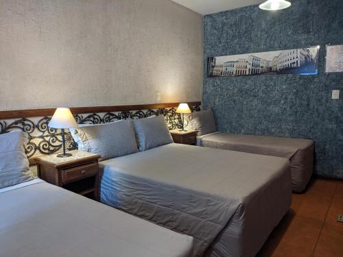 a hotel room with two beds and two lamps at Pousada Brasil Nativo in Cabo Frio