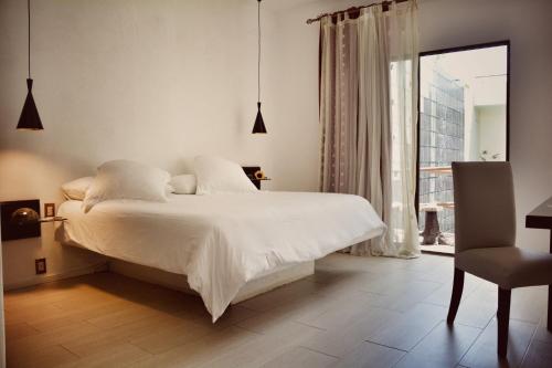 a bedroom with a white bed and a chair at Kinbe Hotel Boutique in Playa del Carmen