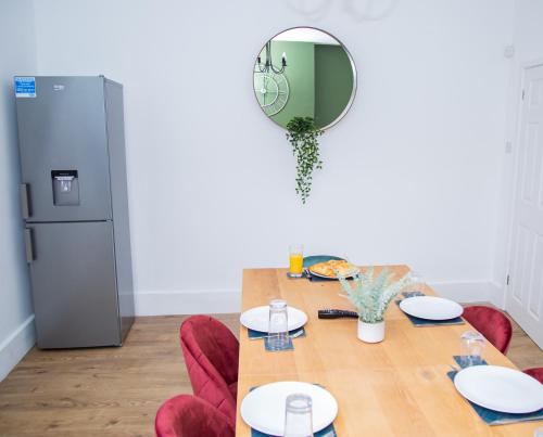 a dining room table with a mirror and a refrigerator at Porchester House Nottingham in Nottingham