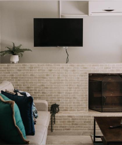 a living room with a brick fireplace with a flat screen tv at The Living Collective Villa in Hilton