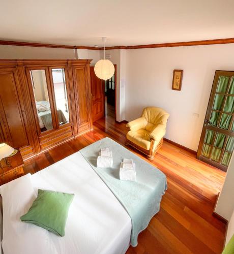 a bedroom with a white bed and a chair at Canary Bio Hostel Tenerife in Los Realejos
