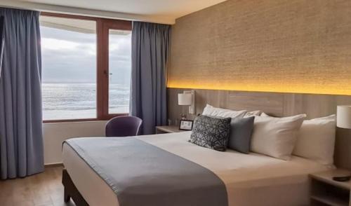 a hotel room with a bed with a view of the ocean at Yachting Hotel Quintero in Quintero