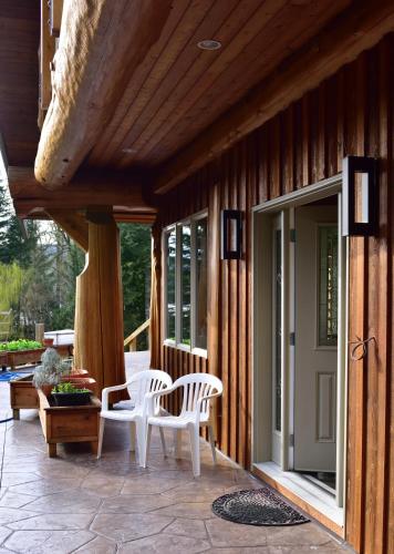 a porch with two white chairs and a door at The Rockwell-Harrison Guest Lodge in Harrison Hot Springs