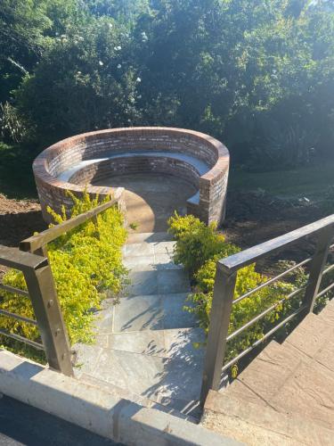 een stenen bank op een loopbrug in een park bij The Living Collective Villa in Hilton