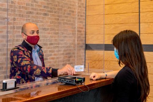 a man with a red face mask standing at a counter with a woman at Hotel 1868 in Cambridge