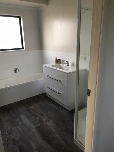 a white bathroom with a sink and a shower at A Place in the Paddock in Matamata