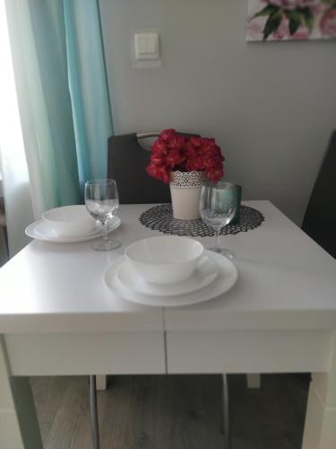 a white table with two plates and glasses on it at Apartament Agata in Giżycko