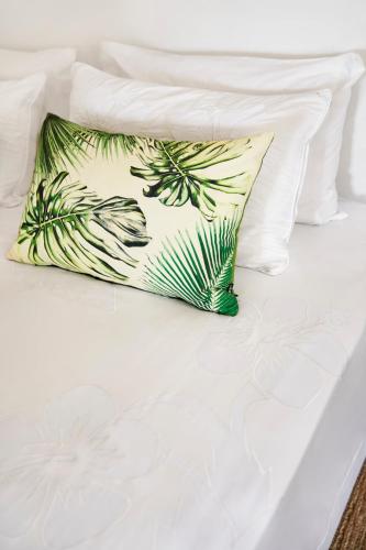 a pillow sitting on top of a white bed at Motu Beachfront Art Villas in Rarotonga