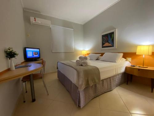 a bedroom with a bed and a desk with a computer at Hotel Canada in Ribeirão Preto