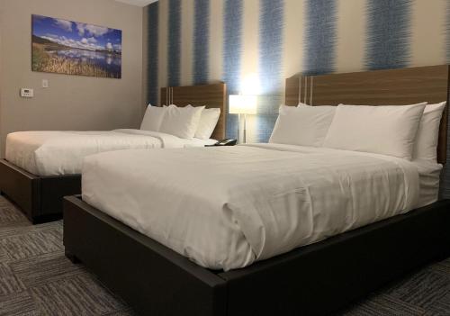 a hotel room with two beds with white sheets at Meridian Inn & Suites Regina Airport in Regina