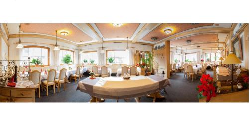 una sala da pranzo con tavoli, sedie e finestre di Hotel Pfrontener Hof a Pfronten