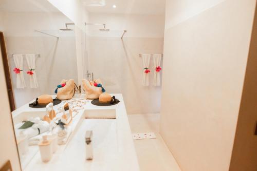 a white bathroom with hats sitting on a counter at Madeiro Beach Hotel in Pipa