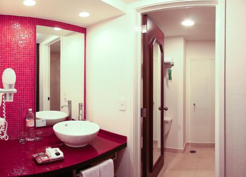 La salle de bains est pourvue d'un lavabo et d'un mur en carrelage rouge. dans l'établissement Fiesta Inn Xalapa, à Xalapa
