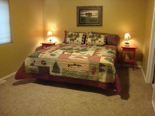 1 dormitorio con 1 cama con 2 lámparas en 2 mesas en Geyser Mountain Home en West Yellowstone