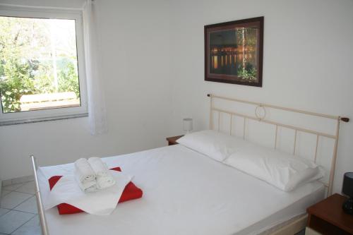 a bedroom with a white bed and a window at Apartments Irena Krk in Krk
