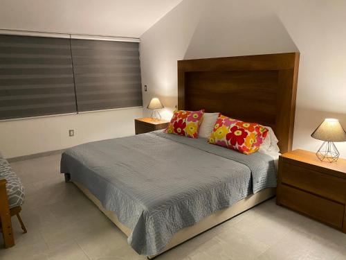 a bedroom with a bed with two lamps and two tables at Casa de las Palmeras Lomas de Cocoyoc in Atlatlahucan