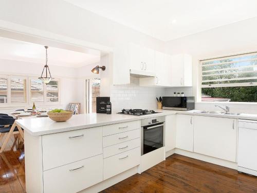 a white kitchen with white cabinets and a sink at Kookaburra Cottage in Bowral