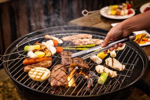 a person is cooking meat and vegetables on a grill at KensingtonResort JirisanHadong in Hadong