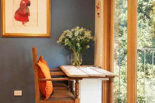 a dining room with a table and a vase of flowers at Koko Guesthouse - One Bedroom Option in Olinda