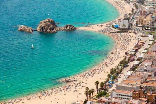 a beach with a large group of people in the water at Apartamento con piscina en el centro de Blanes in Blanes