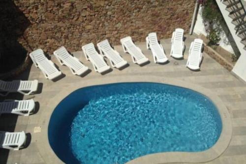 un grupo de sillas blancas y una piscina en Apartamento con piscina en el centro de Blanes en Blanes