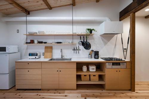 una cucina con armadi in legno, lavandino e frigorifero di Japan Sessions KANZAKI 02 ad Osaka