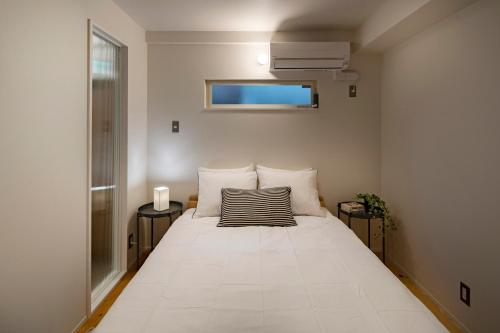 un grande letto bianco in una stanza con finestra di Japan Sessions KANZAKI 02 ad Osaka