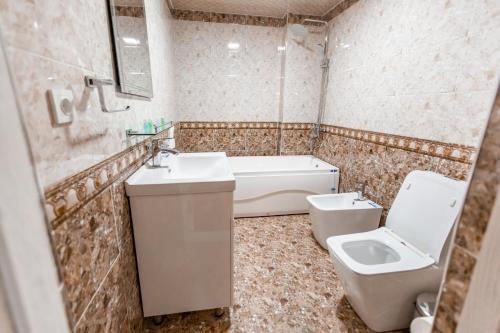 a bathroom with a toilet and a sink and a bath tub at OydinPlaza Hotel in Namangan