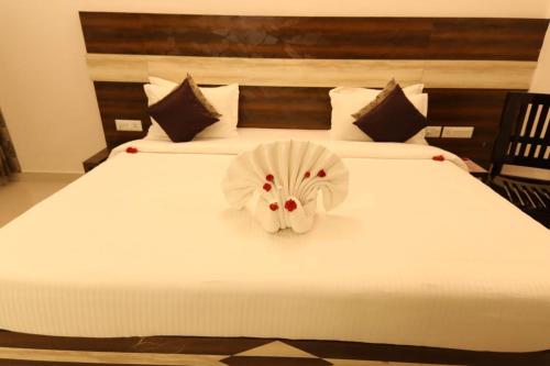 a white bed with a flower decoration on it at Sri Gnana Vedha Beach Residency in Velānganni