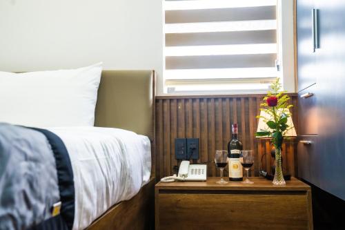a bedroom with a bed with a phone and wine glasses at Rose Hotel Quảng Bình in Dong Hoi