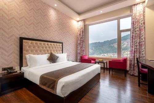 a hotel room with a bed and a desk and a window at The Orchid Shimla in Shimla