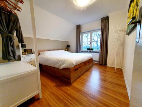 een slaapkamer met een bed en een houten vloer bij B & B de Stok in Sint-Oedenrode