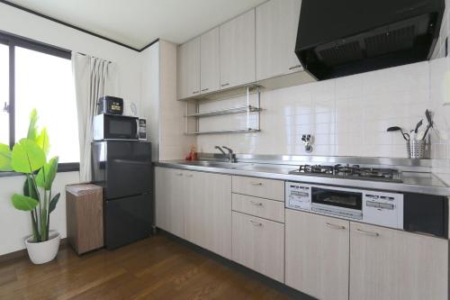 a kitchen with white cabinets and a stainless steel appliances at Liz3 Guest House Liz Nakazakicho in Osaka