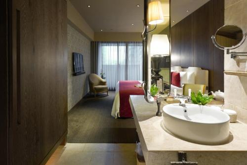 a hotel room with a sink and a bedroom at Palais de Chine Hotel in Taipei
