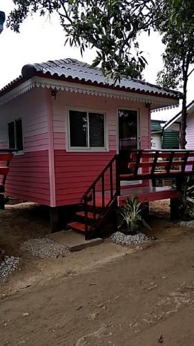 a red and white house with a bench in front of it at ชายเขาโฮมสเตย์ in Kanchanaburi